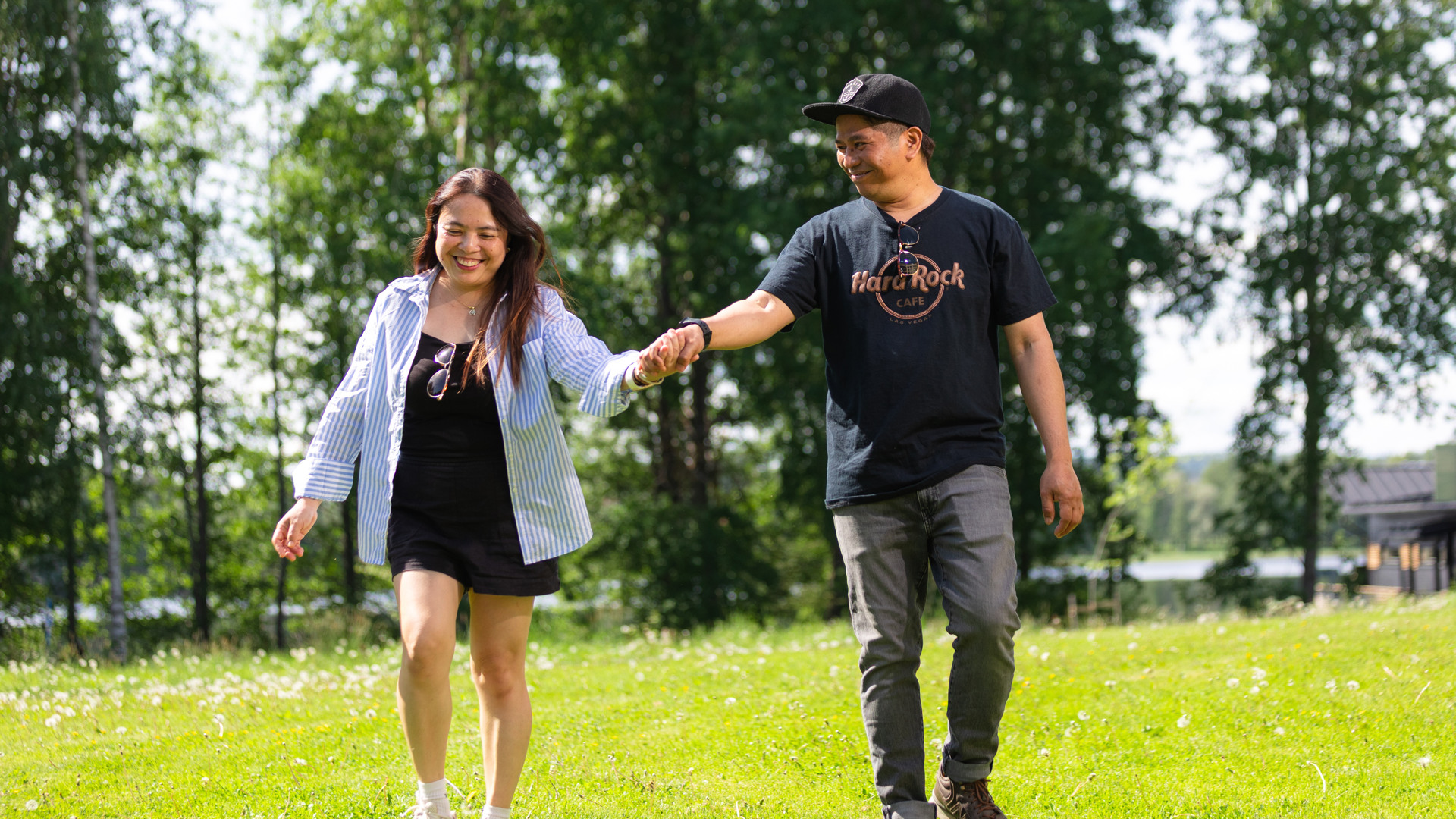 Two people walking hand in hand together in a sunny park with smiling faces