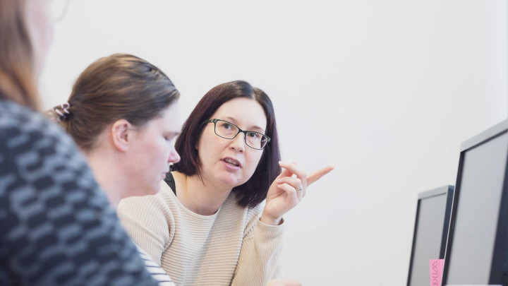 Kuvassa naiset tekevät yhteistyötä tietokoneen ääressä