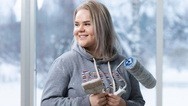 Maalariopiskelija siveltimien kanssa.