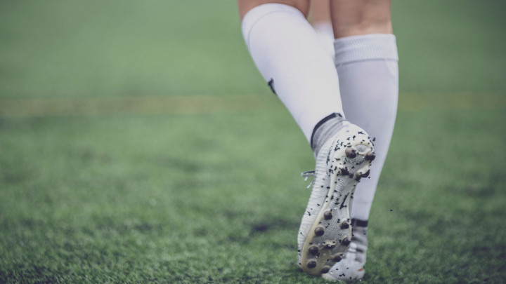 Jalkapallon pelaaja kävelee nappikset jalassa.