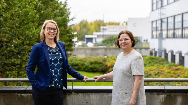 Kaksi henkilöä Gradian kampuksen piha-alueella syksyllä katsomassa kameraan.
