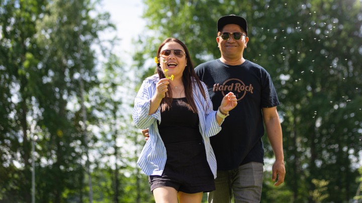 Two people walking together in a sunny park with smiling faces