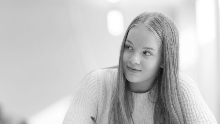 Lukiolaistyttö istuu miettiväisen näköisenä.