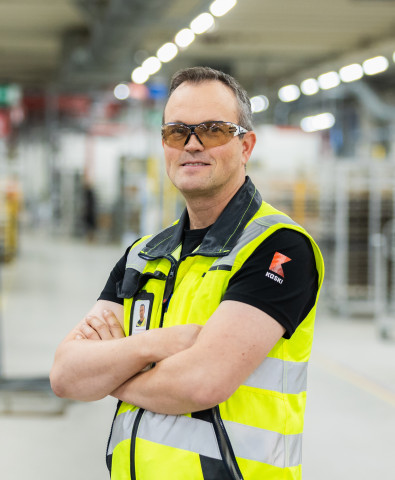 Henkilö suojalasit päässä ja huomioliivi päällä katsoo kameraan.